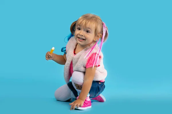 La niña juega en el suelo y come dulces. Foto sobre fondo azul. Concepto de vacaciones, Halloween — Foto de Stock