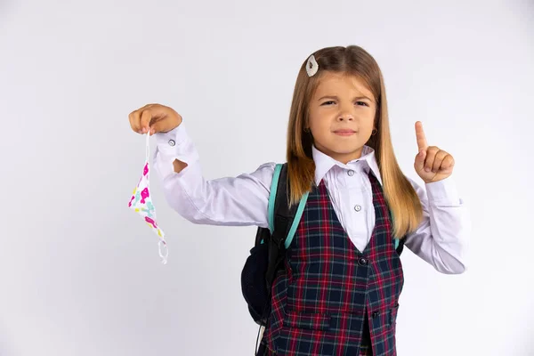 Una chica de uniforme vino de la escuela y se quita la máscara protectora, con la cara disgustada. Cuarentena. — Foto de Stock