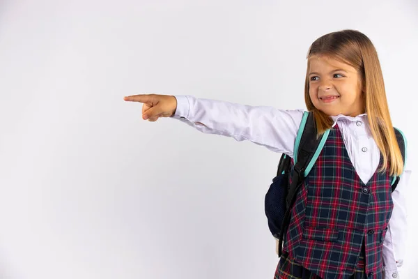 Colegiala, con una sonrisa sonriente, señalando con su dedo índice, a un lugar con espacio en blanco para el texto, la publicidad —  Fotos de Stock