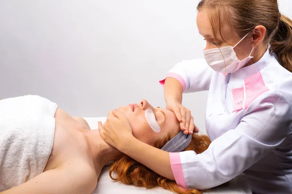 Estetista fa un massaggio facciale professionale ad una giovane ragazza. Concetto di pelle sana. Foto su sfondo bianco — Foto Stock