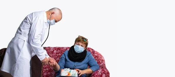 Banner, formato lungo. Un medico mascherato prende un polso delle donne durante una visita medica a casa. Virus e pandemia, concetto isolato. Foto con spazio laterale vuoto — Foto Stock
