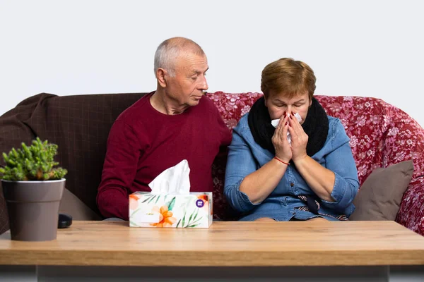 Ο σύζυγος φροντίζει μια άρρωστη σύζυγο που τρέχει μύτη και πονάει ο λαιμός της. Ένα ηλικιωμένο ζευγάρι παλεύει στο σπίτι με ιογενή λοίμωξη και πονόλαιμο.. — Φωτογραφία Αρχείου