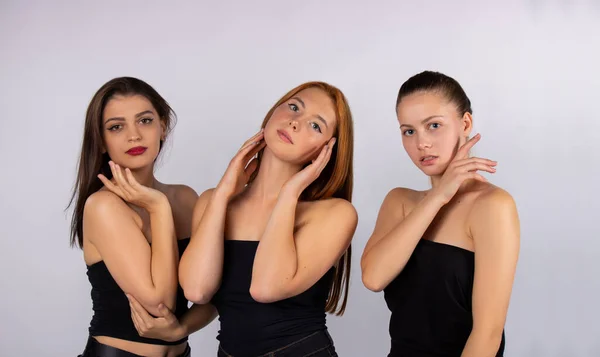 Três meninas bonitos e atraentes posando em um fundo cinza no estúdio. Spa e conceito de beleza corporal. Corpo e cuidado — Fotografia de Stock