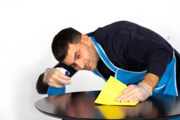 Jovem limpa a mesa com um pano e spray caseiro. Estereótipos de género. Foto sobre um fundo branco. — Fotografia de Stock