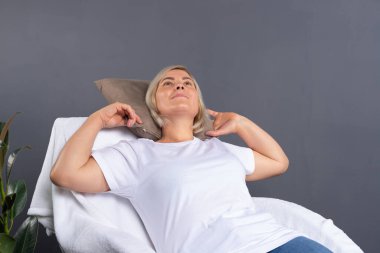 Sakin yaşlı kadın evdeki rahat koltukta dinleniyor, mutlu kadın dinleniyor ve hayaller kuruyor, arkasına yaslanıyor. Yüksek kalite fotoğraf