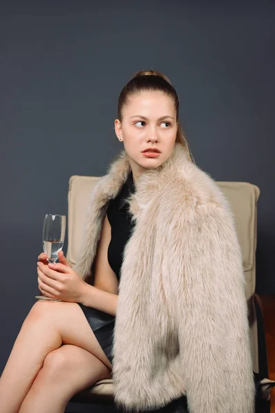 Allvarlig Flicka Firar Håller Ett Glas Champagne Päls Medan Sitter — Stockfoto
