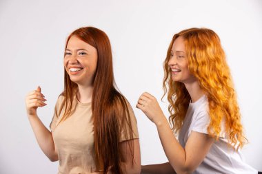 İki kızıl saçlı kız arkadaş eğleniyor. Beyaz arka planda fotoğraf. Yüksek kalite fotoğraf