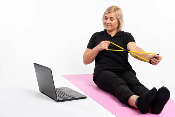 Mulher Sênior Segura Uma Banda Resistência Tapete Frente Laptop Fitness — Fotografia de Stock