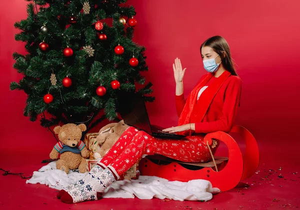 Uma Menina Trenó Uma Árvore Natal Casa Uma Máscara Médica — Fotografia de Stock