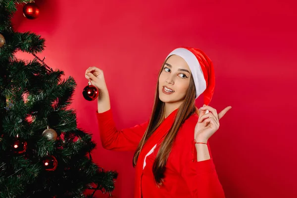 Uma Menina Chapéu Papai Noel Decora Uma Árvore Natal Fundo — Fotografia de Stock