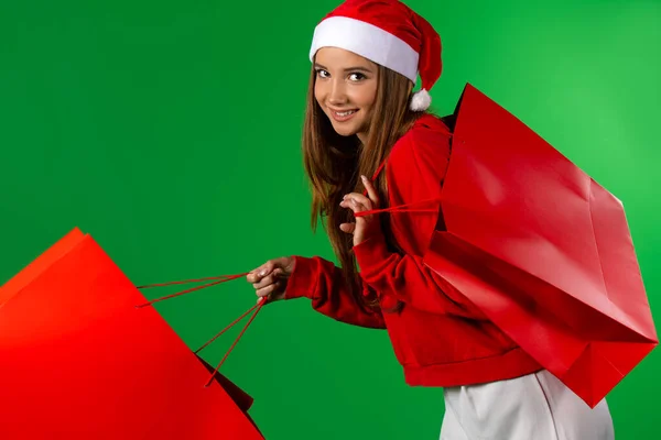 Meisje Kerstman Kleding Hoed Met Rode Geschenkzakjes Een Groene Achtergrond — Stockfoto