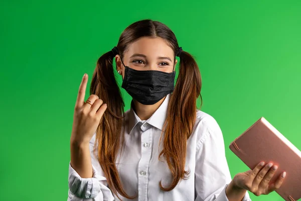 Menina Estudante Uma Máscara Respiratória Com Livro Posando Fundo Verde — Fotografia de Stock