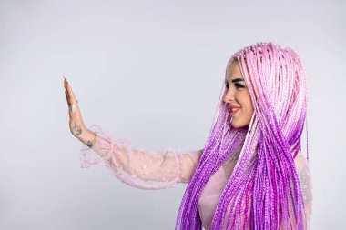 Örgülü, uzun pembe saçlı, elini ileri doğru uzatan modern bir kızın profil fotoğrafı durduğunu gösteriyor..