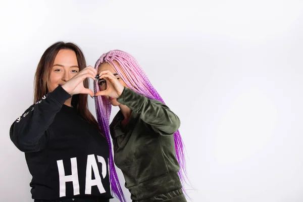 Las chicas de moda se toman de la mano en forma de corazón sobre fondo blanco con espacio lateral vacío. Devolver, caridad y solidaridad —  Fotos de Stock