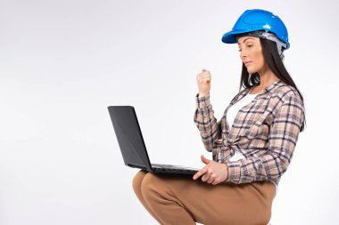Serious woman architect communicates by video call on computer and shows a fist. White background. High quality photo