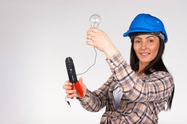 A woman electrician repairs a light with a light bulb in her hands and looks with a smile at the camera. White background. High quality photo