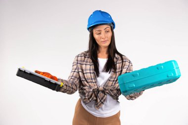 Handywoman in a helmet, blue hard hat looking at two suitcases for tools. Combat gender stereotypes. High quality photo