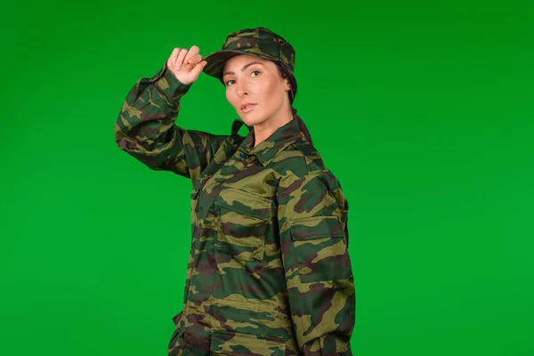 Serious woman in military uniform posing and looking at the camera on green background, space for advertisment. High quality photo