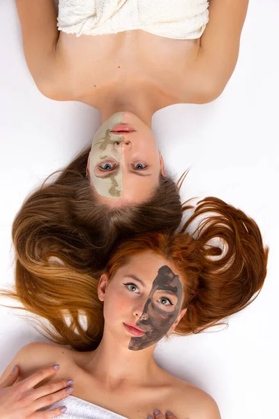 Dvě Dívky Obličejovými Maskami Polovinu Obličeje Leží Podlaze Zdravá Pleť — Stock fotografie
