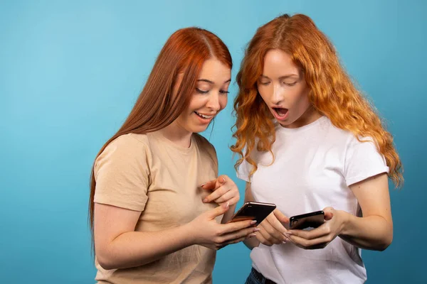 Surprised Girlfriends Blue Background Looking Excited Smartphones People Lifestyle Concept — Stock Photo, Image