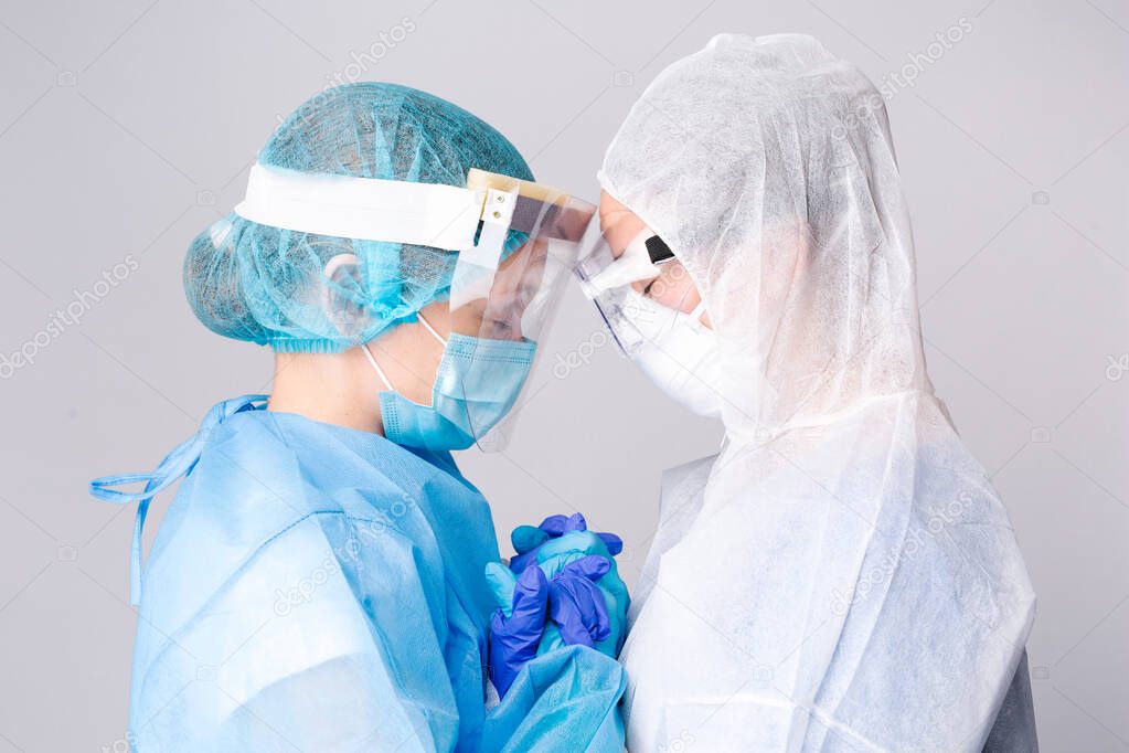 Two sad doctors comfort each other outside the intensive care unit. Pandemic and healtcare concept on white background. High quality photo
