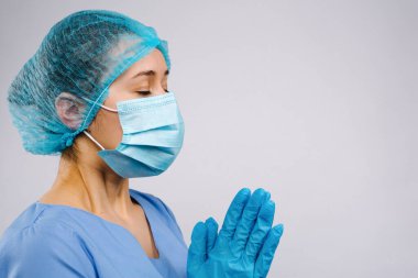 Koronavirüs salgını sırasında üniformalı bir doktor dua ediyor. Beyaz bir arka planda çok çalışan bir doktorun duygusal stresi. Yüksek kalite fotoğraf