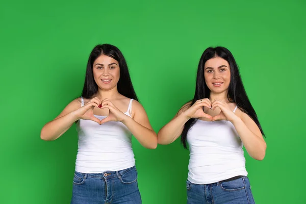 Irmãs Gêmeas Mostram Coração Suas Mãos Sobre Fundo Verde Dia — Fotografia de Stock