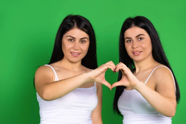 Irmãs Gêmeas Fundo Verde Seguram Suas Mãos Forma Coração Amor — Fotografia de Stock