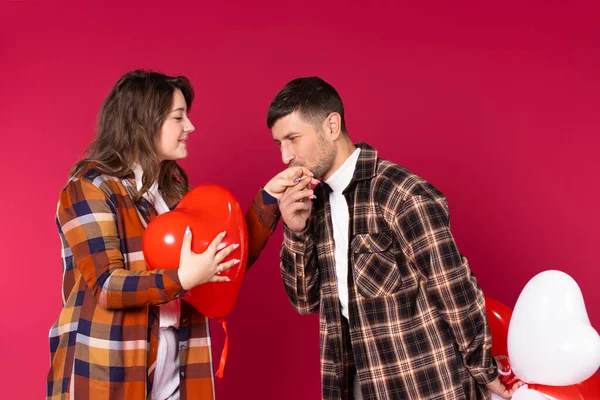 Aşık Bir Adam Kırmızı Arka Planda Elinde Balonlarla Karısının Elini — Stok fotoğraf