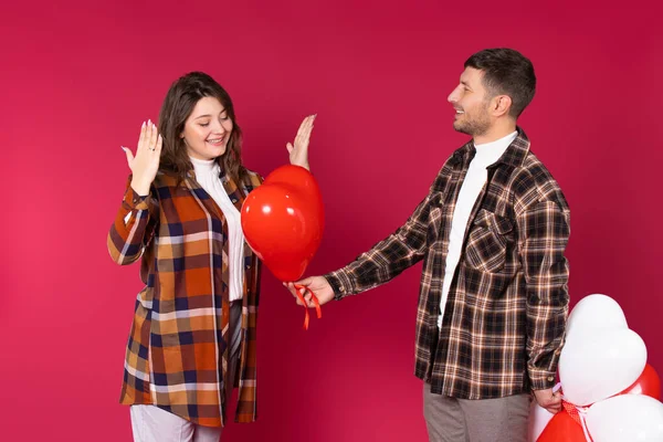 Kırmızı Arka Planda Kırmızı Kalp Balonu Veren Sevgilileriyle Şaşırmış Bir — Stok fotoğraf
