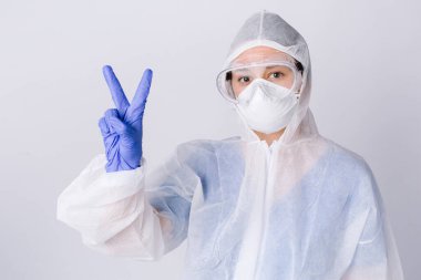 Koruyucu cüppeli doktor zafer ve barış işareti gösteriyor. Virüsü yenmek. Beyaz arka plan. Yüksek kalite fotoğraf