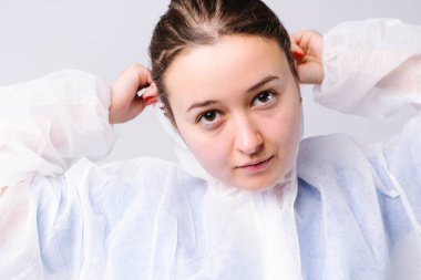 Tatlı bayan doktor beyaz bir arka plana koruyucu bir önlük giyer. Büyütülmüş fotoğraf. Virüsle mücadele kavramı. Yüksek kalite fotoğraf