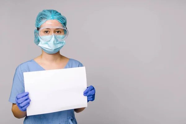 Sjuksköterska Medicinsk Skyddsuniform Håller Ett Blankt Vitt Ark Grå Bakgrund — Stockfoto