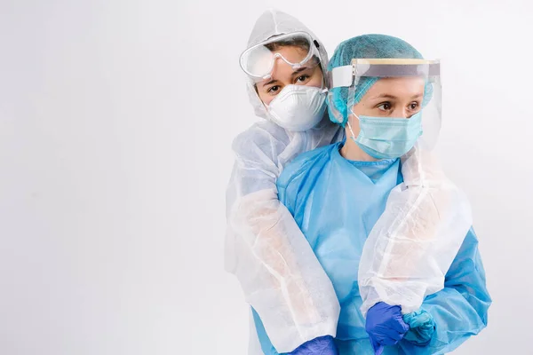 Tired doctors in protective suits are hugged and supported looking to the side. Support in difficult times for them. Side space. High quality photo