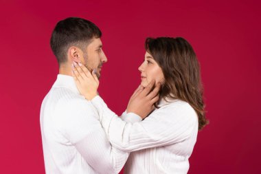 Sevgilim, birbirinizin gözlerine bakın ve nazikçe yüzünüze dokunun. Kırmızı arka plan. Sevgililer Günü. Yüksek kalite fotoğraf