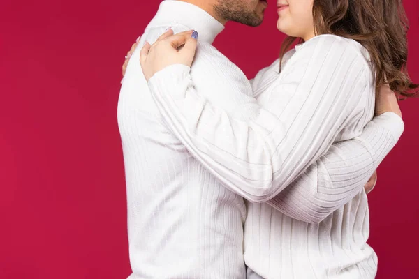 흰 스웨터를 입은 한 부부가 빨간 배경을 껴안고 있는 사진이 확대되었다. 발렌타인데이에 모든 연인들의 개념. — 스톡 사진