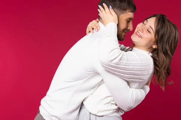 Jeune couple souriant amoureux embrassant sur fond rouge avec espace latéral vide. Saint Valentin — Photo