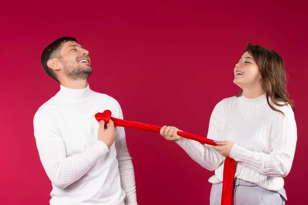 Kırmızı arka planda mutlu bir çift. Kız, erkeğin göğsünden bir kalp söküyor. Sevgililer Günü konsepti. — Stok fotoğraf
