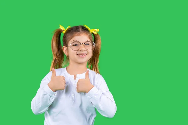 Retrato de uma garota bonita que mostra sorrisos de classe e olha para a câmera. Fundo verde e espaço lateral. — Fotografia de Stock