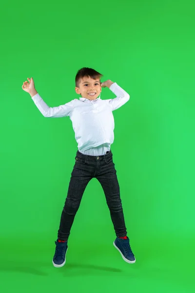 Полная фотография в воздухе. Улыбающийся мальчик прыгает на зеленом фоне. Пустое пространство. — стоковое фото