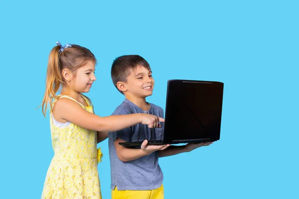 Los niños felices sonríen y se sientan en el portátil. Fondo azul. Pasatiempo. Tecnologías. Emociones infantiles. — Foto de Stock