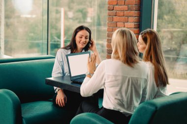İş kadını beyaz gömlekler giyip birbirine bakıyor ve masada dizüstü bilgisayarla otururken gülümsüyor. İş konsepti.