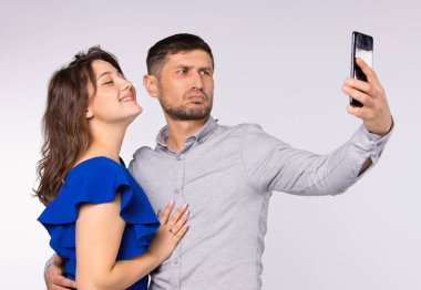 Otantik çift akıllı telefondan selfie çeker. Gri arka plan. Zaman geçirme konsepti. Teknolojiler.