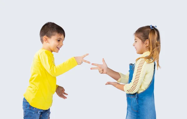 Lindos niños juegan piedra, tijeras de papel y se divierten sobre un fondo blanco. — Foto de Stock