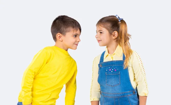 Söta leende barn ser varandra i ögonen i casual kläder på en vit bakgrund. — Stockfoto