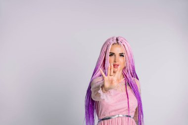 Pembe saçlı blogcu fotoğrafı atmak için öne uzandı. Beyaz arka planda dur. Yan beyaz boşluk.