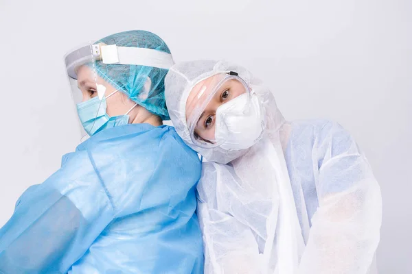 Yorgun doktor hemşireye yaslandı. Gri arka planda tıbbi personelin yorgun çalışma günleri..