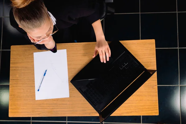 Foto dall'alto. Donna d'affari si siede a un computer in ufficio con i documenti sul tavolo. — Foto Stock