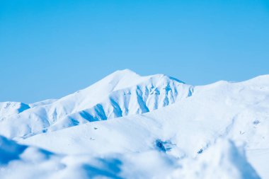 Kar kaplı kayalar ve açık mavi gökyüzü. Güneş parıldıyor, parlıyor.