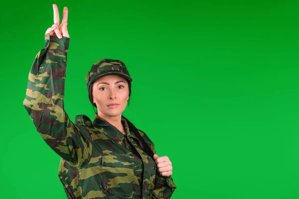 Mujer militar mostrando signo de victoria y paz sobre fondo verde con espacio lateral en blanco para su anunciante — Foto de Stock
